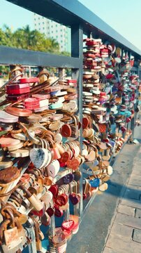 Heart shaped and assorted engraved padlocks clutched to a bridge railing in da nang, vietnam, forming a colorful, symbolic display of love, commitment and shared memories