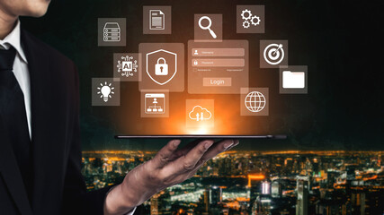 A businessman stands against a glowing night cityscape, holding a tablet displaying digital icons. This represents innovation, technology, and online security solutions in modern business. Gantry © InfiniteFlow