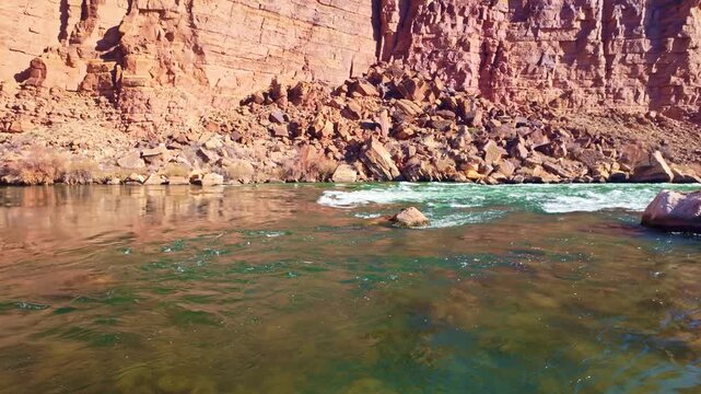 View of Colorado River shoreline flowing through Marble Canyon with desert cliffs and layered landscape