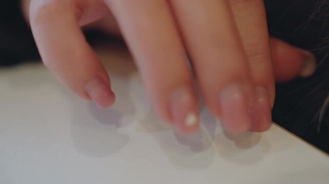 Closeup caucasian teen hand grabbing edge, urgent motion with chipped nails catching light, fingers sliding across white tabletop, implied snatch attempt, tense shallow focus, candid detail, slight