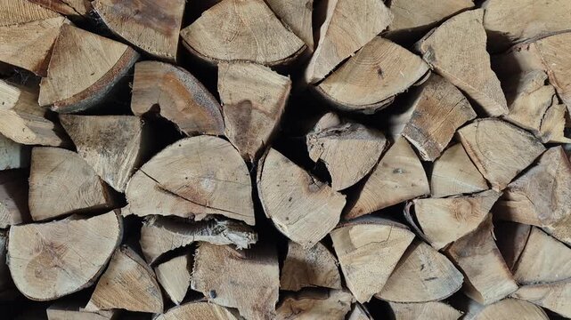 A tightly packed stack of split logs, highlighting the varying textures of raw wood grain and bark.