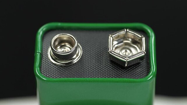 Nine-volt battery, or 9-volt battery - electric battery that supplies a nominal voltage of 9 volts. Green 9-volt battery ready to power devices. Close-up shot video