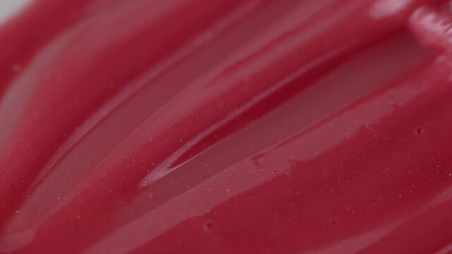 Macro shot of glossy red cosmetic lipstick texture applicator