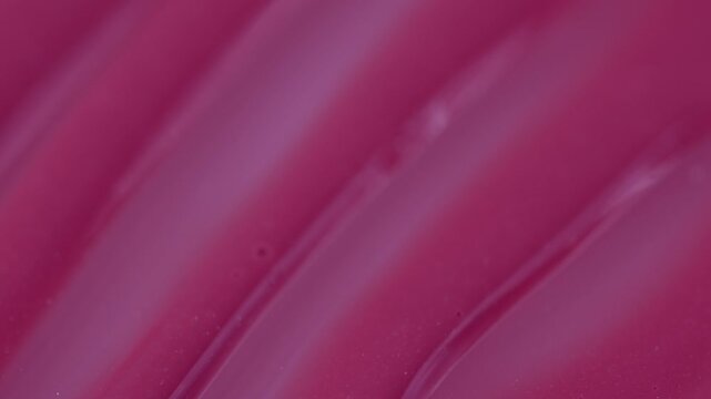 Macro shot of glossy pink cosmetic lipstick texture applicator
