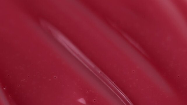 Macro shot of glossy red cosmetic lipstick texture applicator