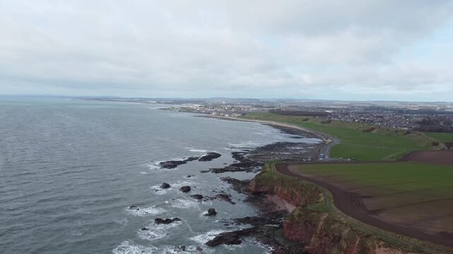 arbroath cliffs east coast of scotland dramatic epic rugged scenery forward movement drone shot red sandstone cliffs stormy sea waves over rocks