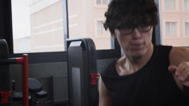 Close up of young Asian man boxing in air, improving technique of punches and dodges during boxing workout in gym