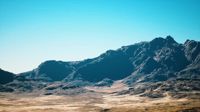 Sunlit desert mountain landscape, azure sky dry plain and rocky ridges bathed in midday light, cinematic drone perspective, warm color grading, rugged boulders