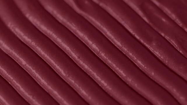 Macro shot of glossy red cosmetic lipstick texture applicator