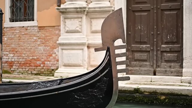 Front section of traditional black watercraft displaying ornamental metal prow near historic building facade