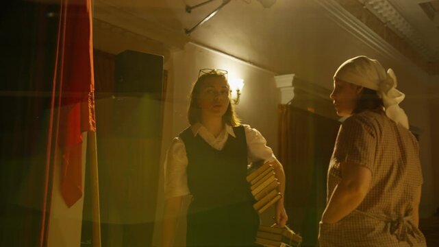 Two performers on a dimly lit stage in an old theater, captured in warm and shadowy lighting as they prepare for a dramatic scene during rehearsal