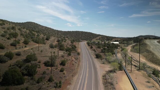 Aerial ascending above two lane highway in High Rolls New Mexico high desert sunny day