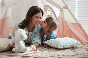 Mother and her daughter with toy near wigwam at home © New Africa