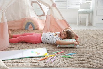 Little girl lying near toy wigwam at home © New Africa