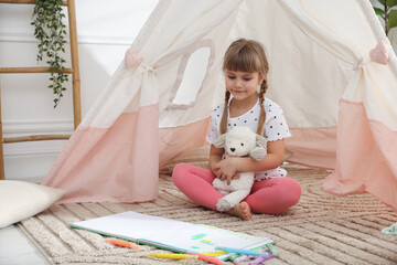 Little girl with toy sheep near wigwam at home © New Africa