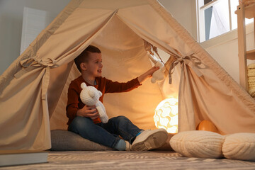 Little boy playing with toys in wigwam at home © New Africa