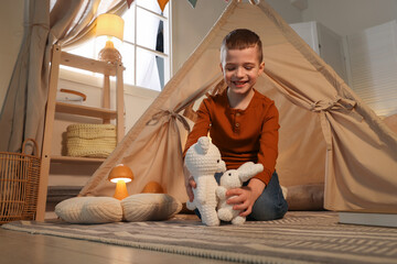 Little boy playing with toys near wigwam at home © New Africa