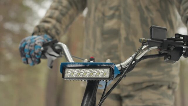 Closeup atv light test on handlebar in pine forest, LED bar beam floods front, rider adjusts mount and wiring with gloved hands, product demo vibe with bright calibration for extreme offroad