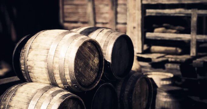 Weathered wooden barrels are stacked next to each other in a dimly lit warehouse, catching the warm glow of the golden hour light. The scene suggests a historic, artisanal atmosphere.