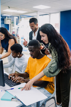 Diverse group of young university students and hispanic teacher using computer in an Academic Environment. Multicultural latin people in technology class in classroom in Latin America