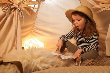 Little girl with drawing of map near wigwam at home. Space for text © New Africa