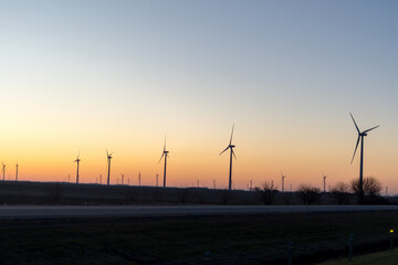 Fototapeta premium Wind turbines at sunset over rural landscape, renewable energy concept