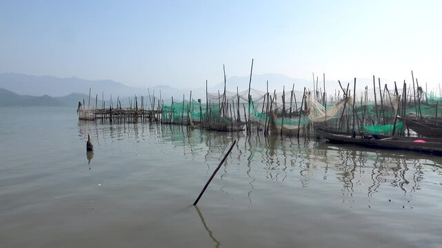 Bottom-mounted seine nets in tidal shallow water in the Gulf of Tonkin at the mouth of the river. Fishing and crabbing. There is an aquaculture