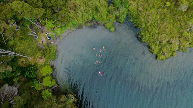 Aerial view of people swimming in a lake bordered by dense green vegetation offering a tranquil scene, Hot Water Beach, Waikato Region, New Zealand.