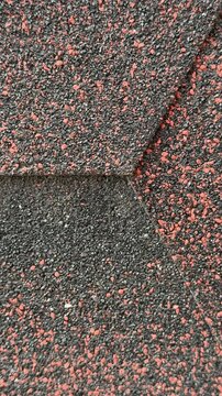 Close-up red hexagonal shingles texture, flexible asphalt roofing with coarse granules, overlapping pattern with subtle weathering.