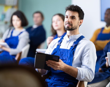 Man in overalls takes notes in an electronic notebook during a refresher course