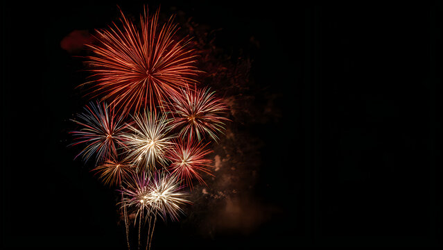 A cluster of vibrant golden and red fireworks exploding against a dark night sky background image