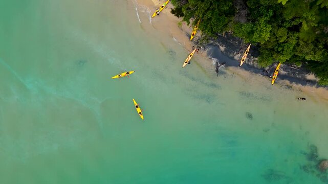 Aerial view of several kayaks resting on a sandy beach next to lush green trees and turquoise waters, Abel Tasman National Park, Tasman Region, New Zealand.