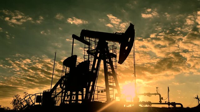 Extraction of petroleum. Oil Pump Jack in motion on Sunrise at Oil Field. Petrolium crude Industrial. Crude pump jack on morning sunrise. Extraction of petroleum in oilfield. Crude petroleum industry.