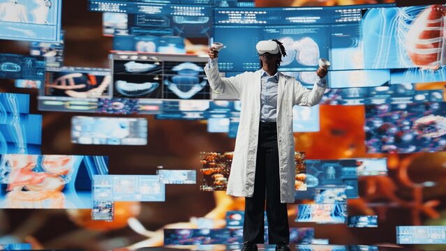 Virtual reality technology used by healthcare expert looking at CT scans, MRI data, and lab analytics on videowall. Scientist in medical research lab reading health data with VR goggles gear, camera A