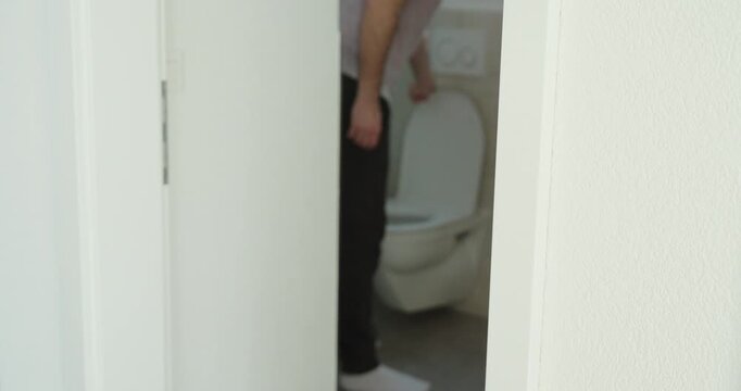 Bathroom shot of a man lifting the toilet seat before urinating while standing, showing hygiene, bathroom etiquette, household routine, cleanliness, and everyday male behavior.