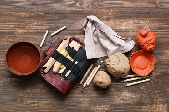 Clay, napkin, bowl and sculptor tools on wooden table