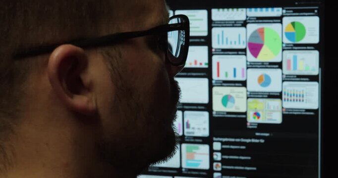 Data Analyst Monitoring Real-Time Business Dashboard on Multiple Screens