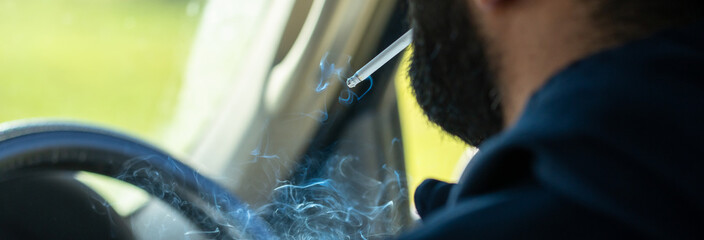 Adult man smoking a cigarette inside a parked car, surrounded by drifting smoke, reflecting solitude, stress, and unhealthy lifestyle habits. © Daniel