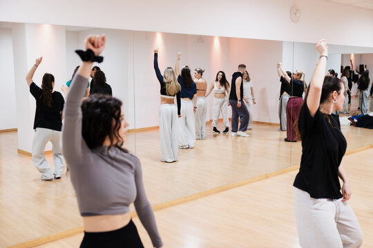 Diverse group of dancers practicing choreography in studio mirror