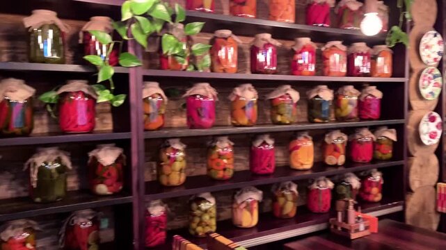 Rustic pantry shelves filled with rows of colorful pickled vegetables in glass jars on wooden shelves, featuring peppers, cucumbers, onions, cafe interior, homemade canning, kitchen decor