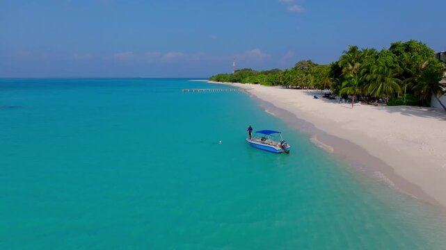 Aerial view of the turquoise waters gently lapping against the pristine white sands of Vashafaru beach, framed by lush green vegetation, Vashafaru, Thiladhunmathee Uthuruburi, Maldives.