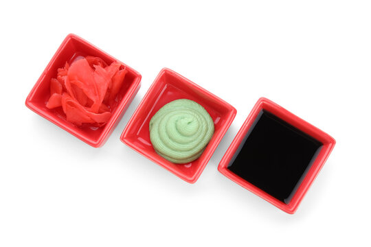 Bowls with pickled ginger, soy sauce and wasabi isolated on white background, closeup