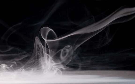 Smoke swirls in dark setting creating soft shapes and patterns over time