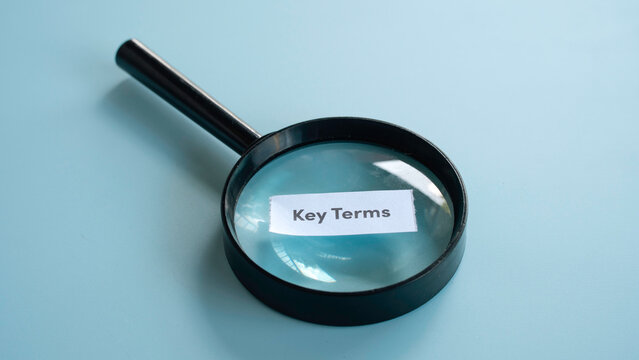 Magnifying glass placed over a paper note with the text key terms for education and contract research concepts.