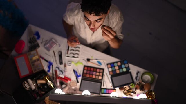 Drag queen artist applying lipstick and makeup at a dressing table mirror before a performance. Top down view of preparation