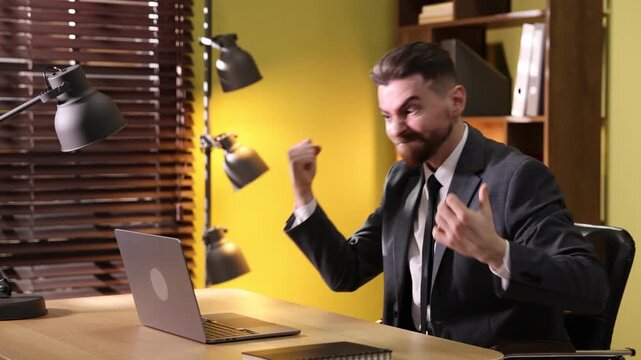 Angry man screaming at laptop in office