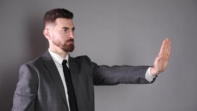 Businessman showing stop sign on grey background