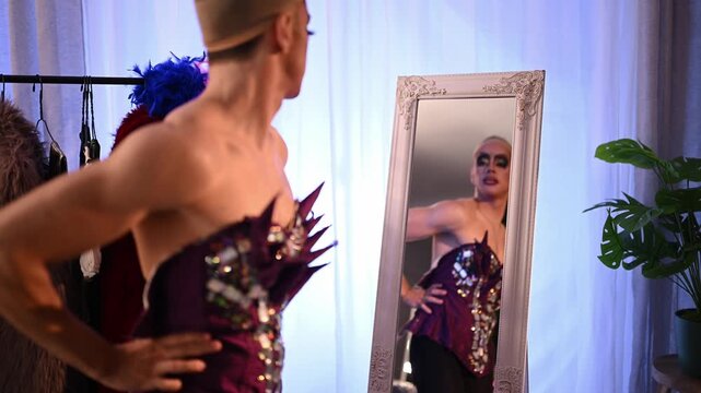 Confident drag queen looking at their reflection in the mirror while wearing a stylish stage corset and professional makeup