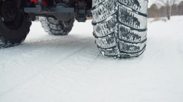 Red atv tire near frozen trail, closeup inspection of rim and tread, mechanic or rider prepping machine for extreme winter run, crisp cold light, textured snow surface, ready for offroad adventure