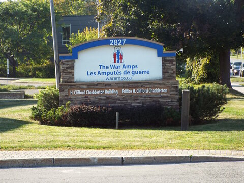 Ottawa, Ontario, Canada &ndash; July 26, 2025: A stone-based monument sign marks "The War Amps  Les Amput&eacute;s de guerre" at the H. Clifford Chadderton Building on Riverside Dr.
